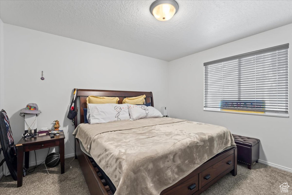 Carpeted bedroom featuring baseboards and a textured ceiling