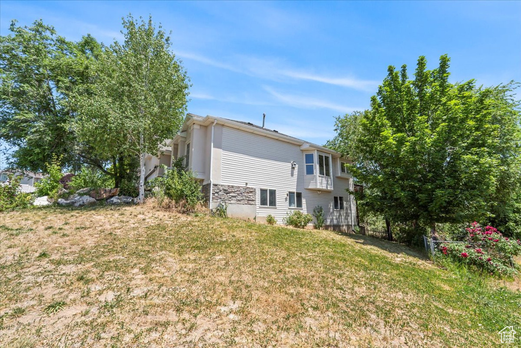 Rear view of property featuring a yard and stone siding