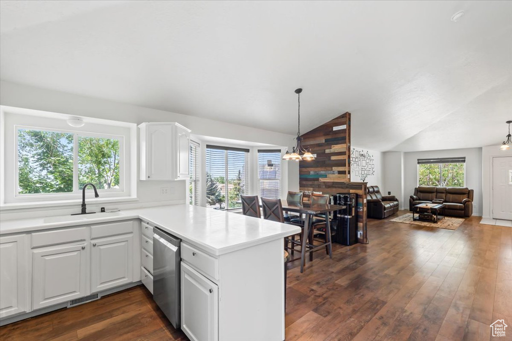 Kitchen featuring stainless steel dishwasher, a peninsula, dark wood-style flooring, vaulted ceiling, and open floor plan