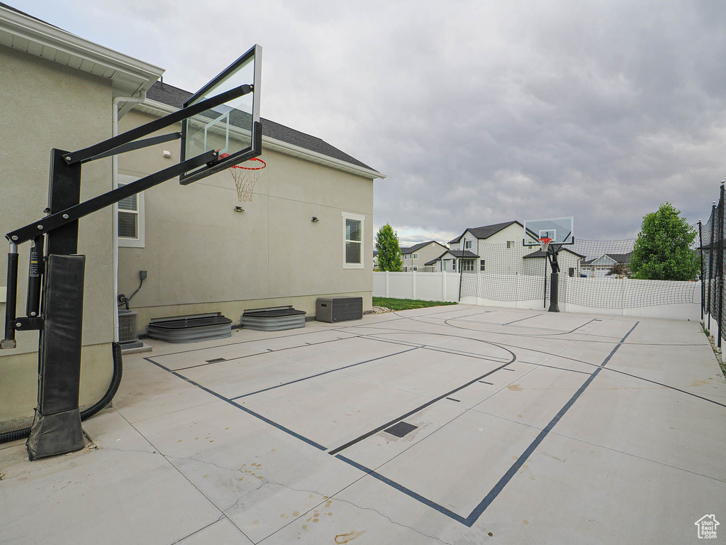 View of sport court featuring basketball hoop and a residential view