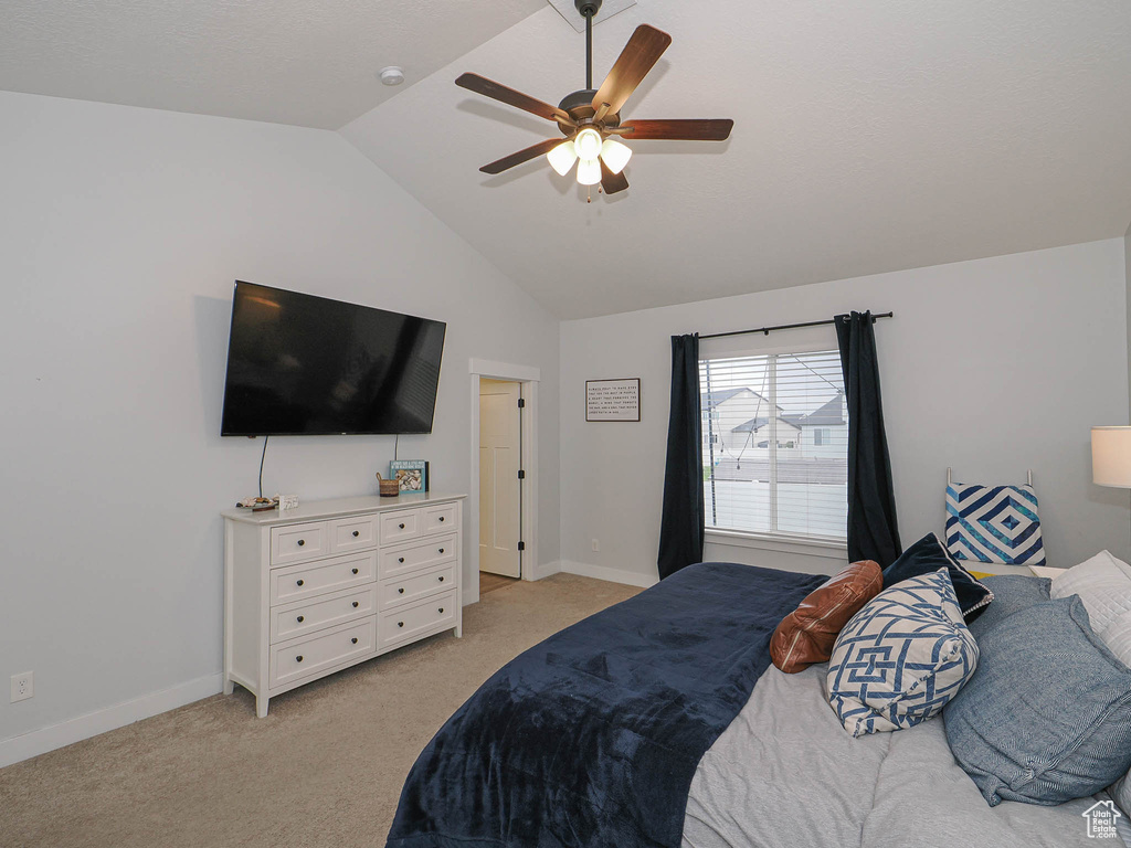 Bedroom with vaulted ceiling, light colored carpet, and a ceiling fan