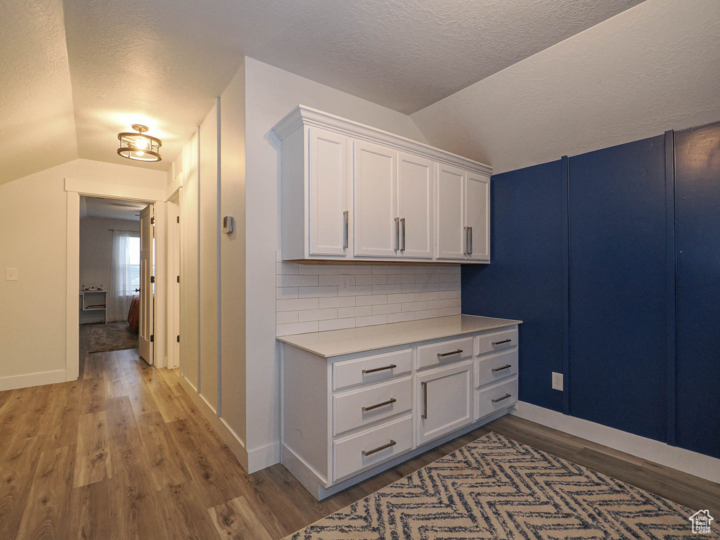 Corridor featuring lofted ceiling, a textured ceiling, and light wood finished floors