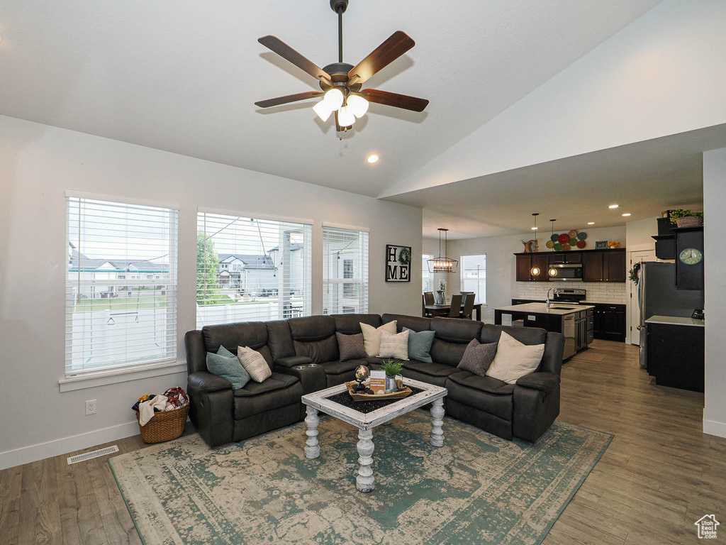 Living area featuring plenty of natural light, ceiling fan, vaulted ceiling, wood finished floors, and recessed lighting