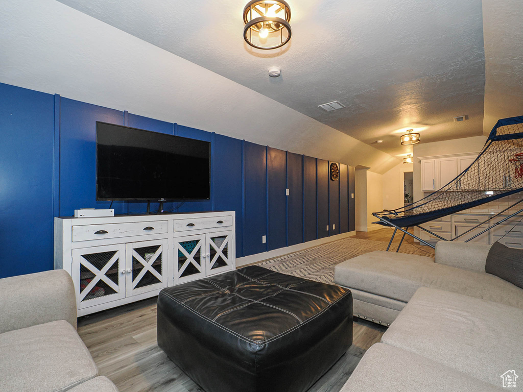 Living area with a textured ceiling, wood finished floors, and lofted ceiling