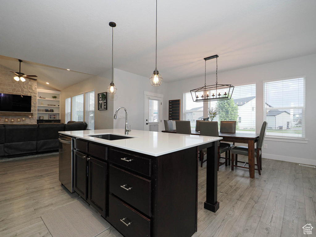 Kitchen with light wood-style flooring, ceiling fan, dark cabinets, light countertops, and lofted ceiling
