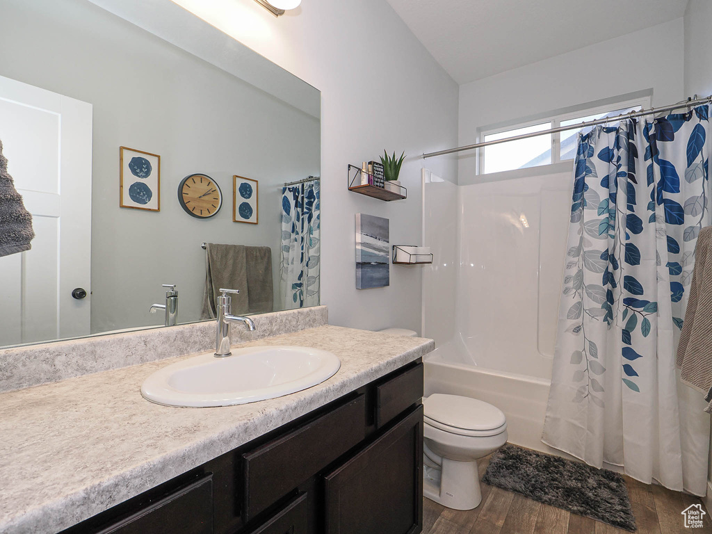Bathroom featuring wood finished floors, vanity, and shower / bath combo