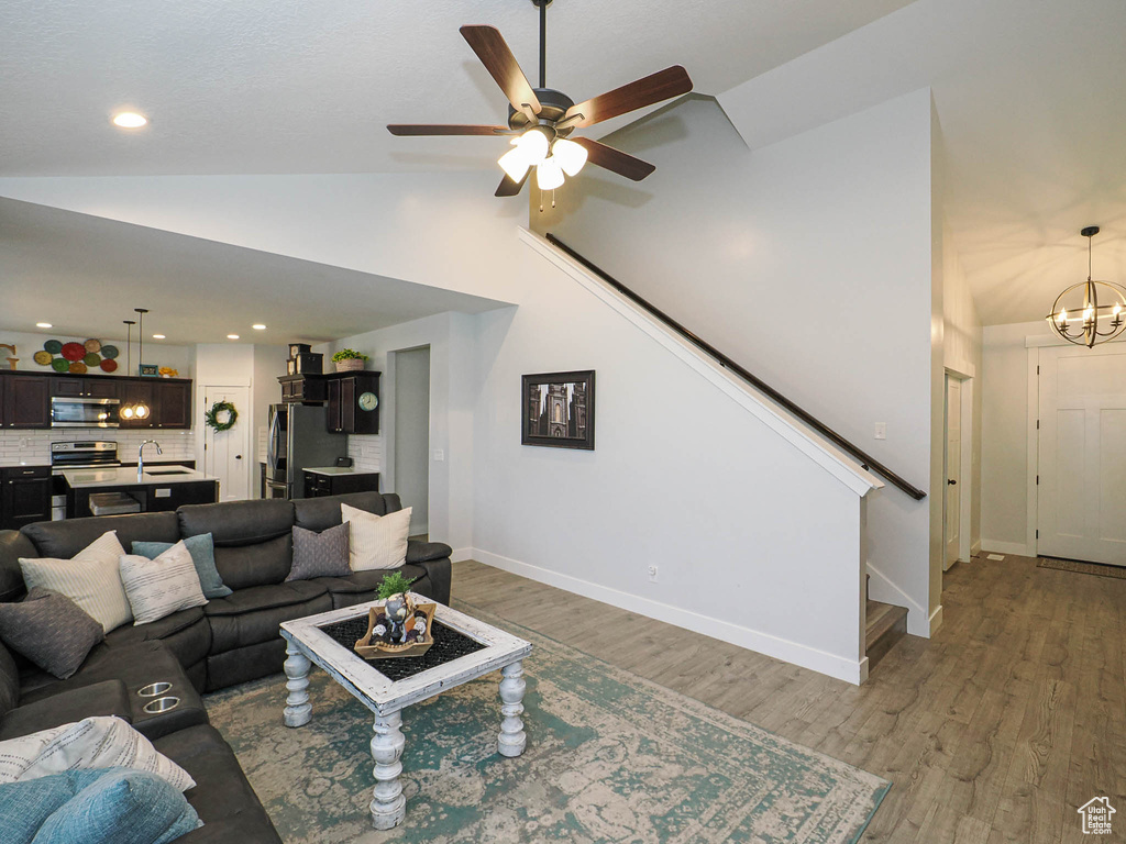 Living area with stairway, light wood-style flooring, ceiling fan, a chandelier, and recessed lighting