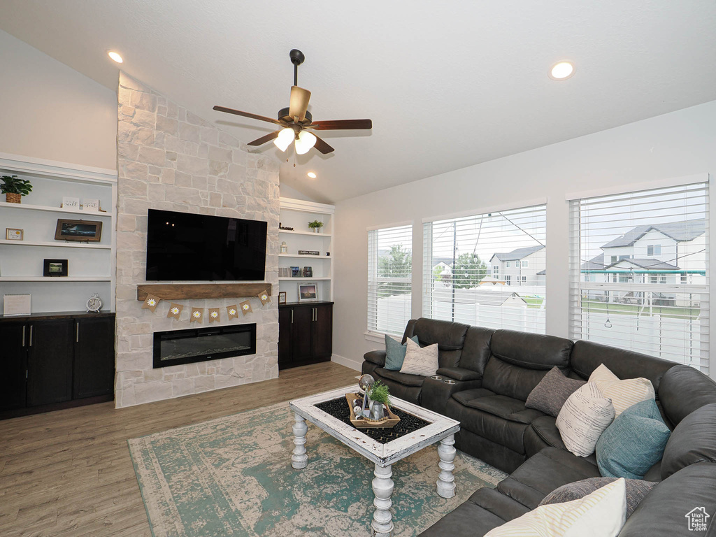 Living area with lofted ceiling, a ceiling fan, a fireplace, wood finished floors, and built in shelves