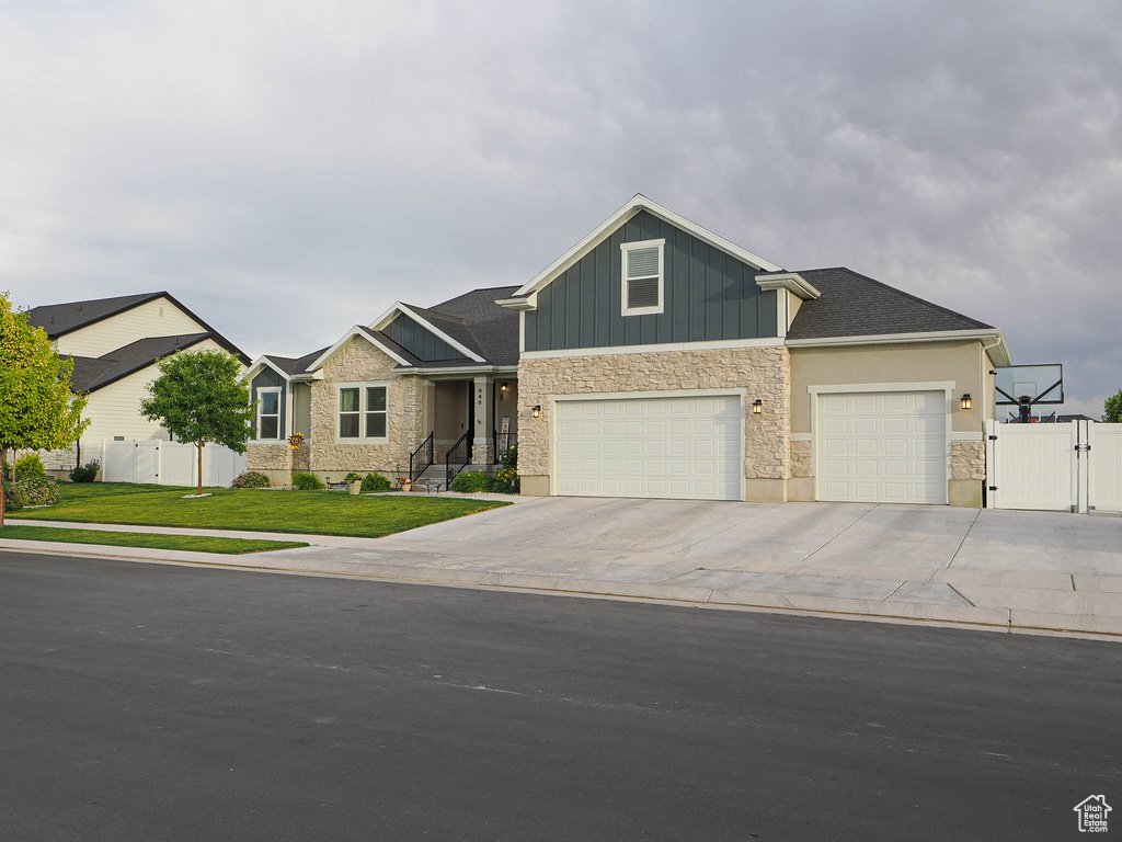 Craftsman inspired home with a gate, stone siding, concrete driveway, board and batten siding, and a garage