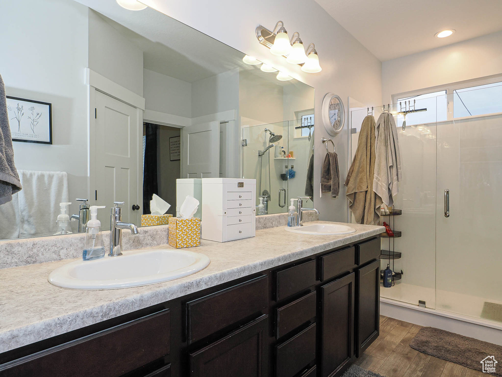 Bathroom with double vanity, a stall shower, and wood finished floors