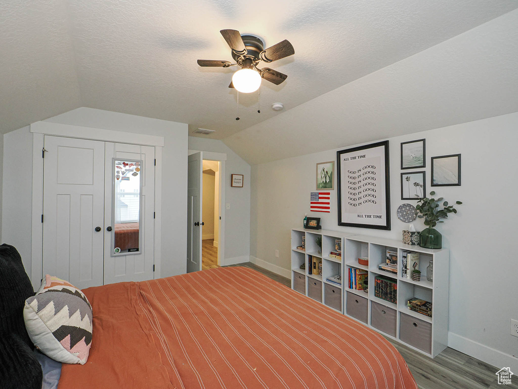 Bedroom featuring wood finished floors, vaulted ceiling, ceiling fan, and a closet