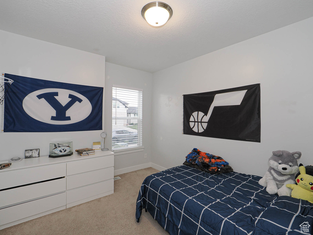 Bedroom with light colored carpet and a textured ceiling