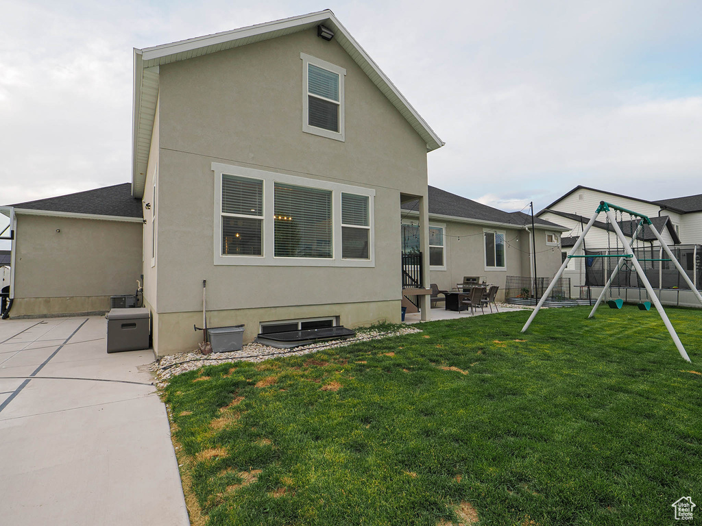 Back of property featuring a patio area, a playground, stucco siding, and roof with shingles
