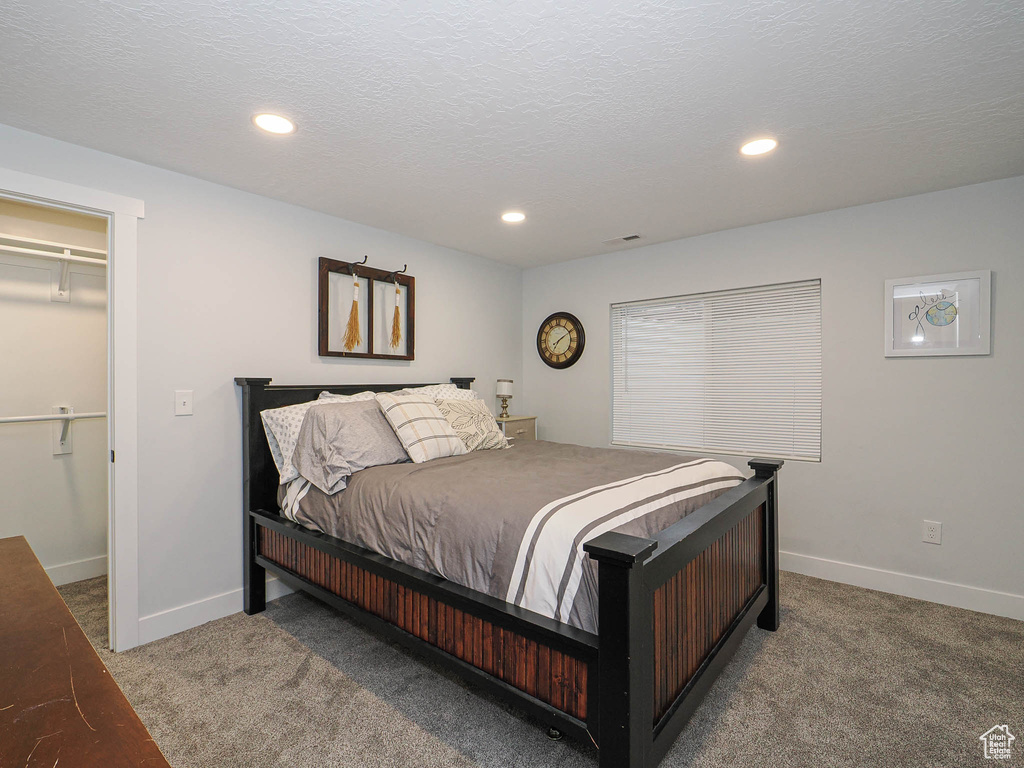 Bedroom featuring carpet floors, a walk in closet, recessed lighting, and a textured ceiling