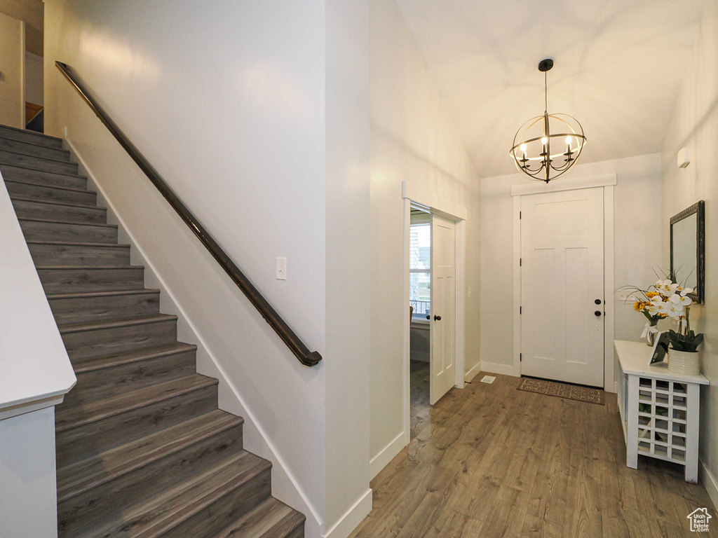 Entryway with stairway, dark wood-type flooring, a chandelier, and vaulted ceiling