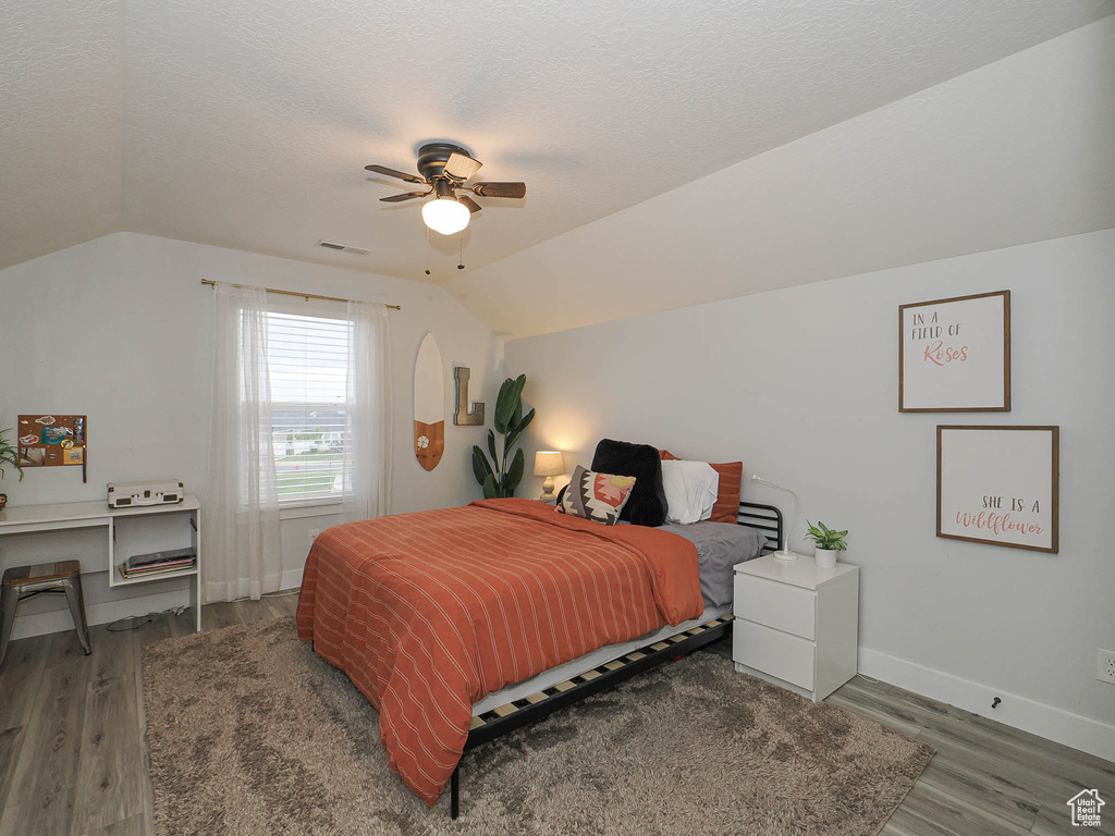Bedroom with lofted ceiling, wood finished floors, a textured ceiling, and ceiling fan