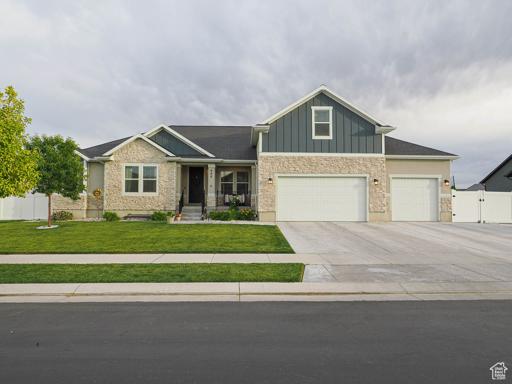 Craftsman-style home featuring stone siding, board and batten siding, concrete driveway, and a garage