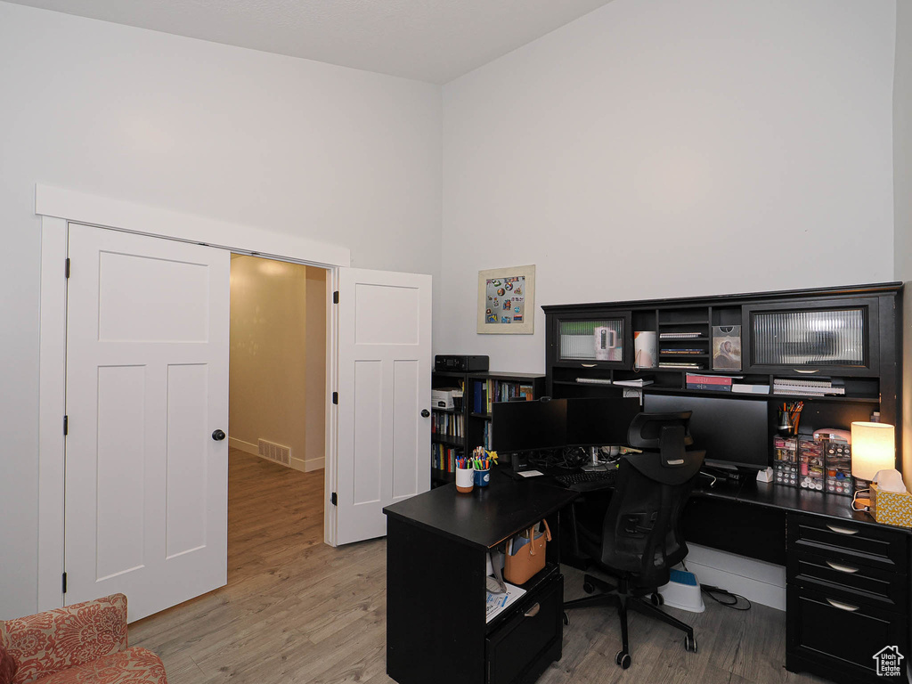 Office with wood finished floors and a towering ceiling