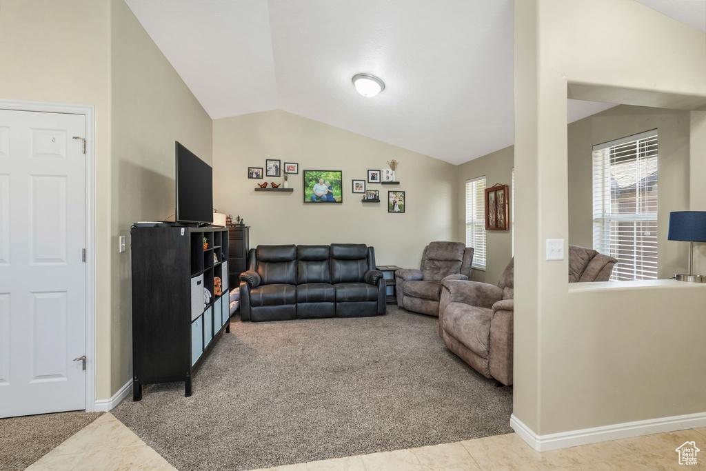 Carpeted living room featuring vaulted ceiling and baseboards