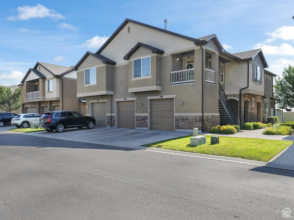 View of building exterior with an attached garage, driveway, stairs, and a residential view