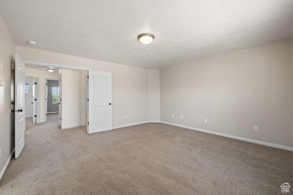 Unfurnished room featuring light colored carpet, a smoke detector, and a textured ceiling