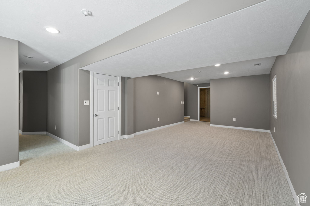 Finished basement with light colored carpet and recessed lighting