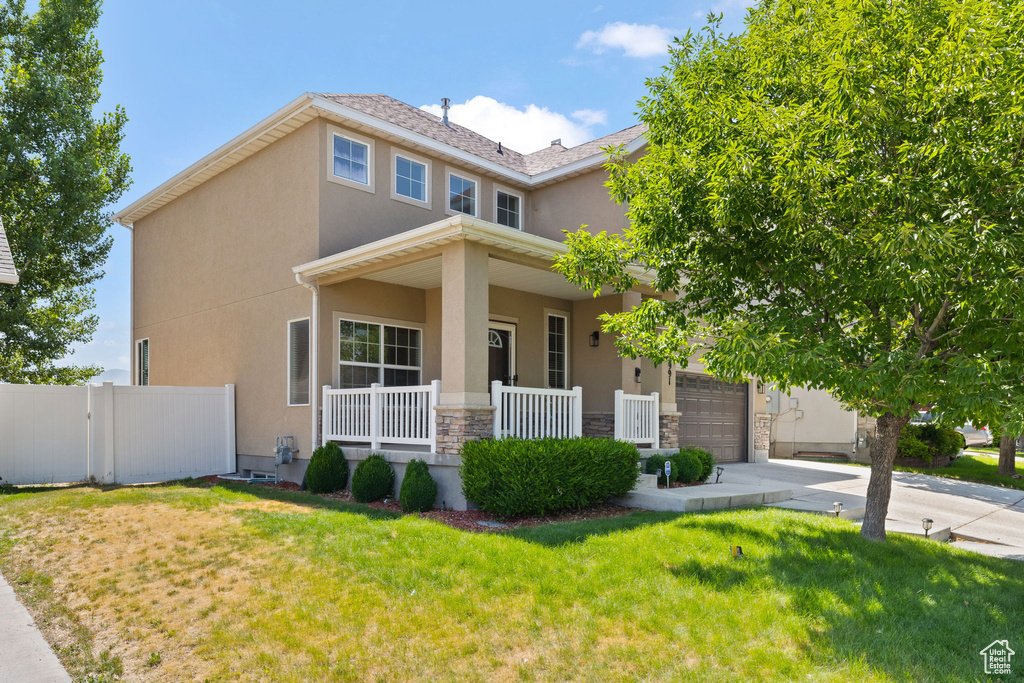 View of front facade with covered porch, stucco siding, concrete driveway, and stone siding