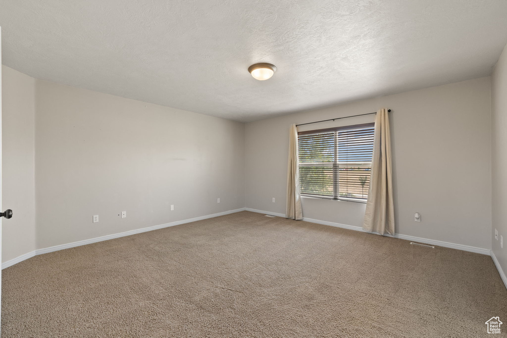 Spare room featuring carpet flooring and a textured ceiling