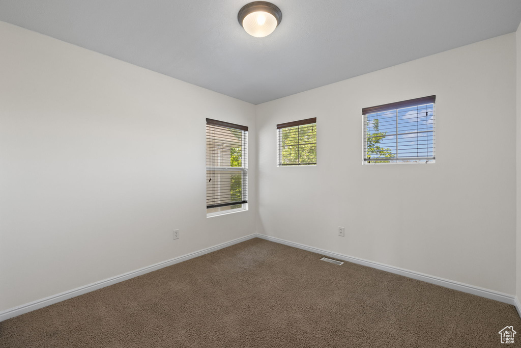 Empty room featuring baseboards and dark carpet