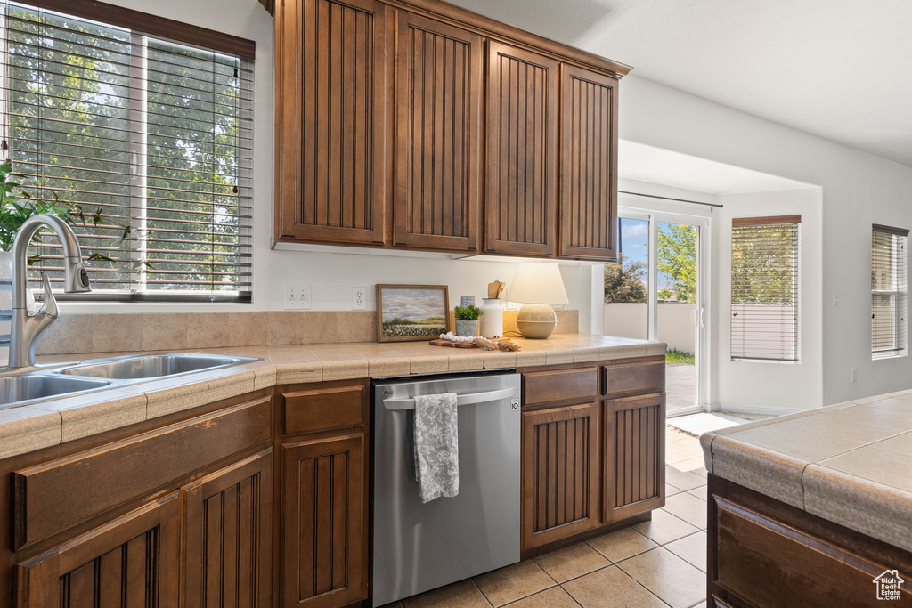 Kitchen with dishwasher, light tile patterned flooring, and tile countertops