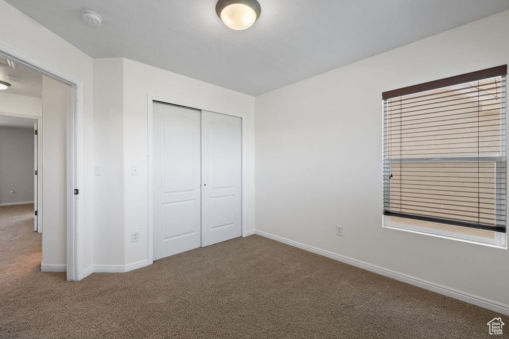 Unfurnished bedroom featuring carpet flooring and a closet