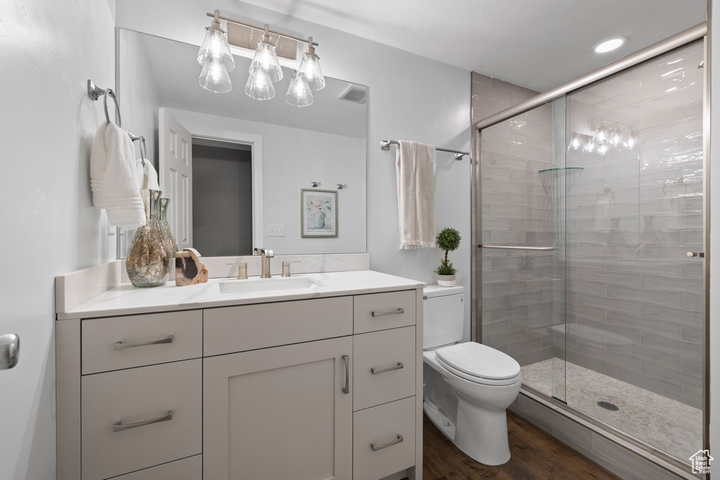 Full bathroom with a stall shower, vanity, and wood finished floors