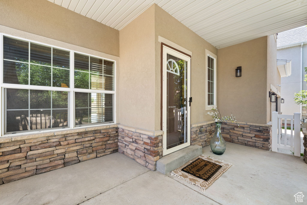 View of exterior entry featuring stucco siding, stone siding, and covered porch
