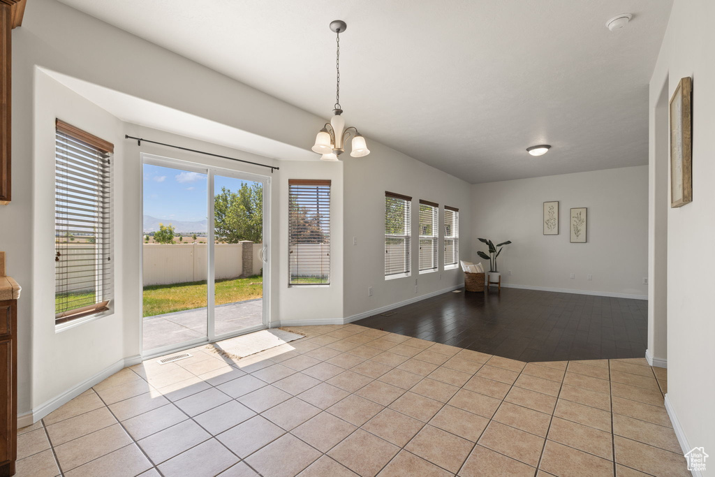 Unfurnished dining area with a chandelier and light tile patterned floors