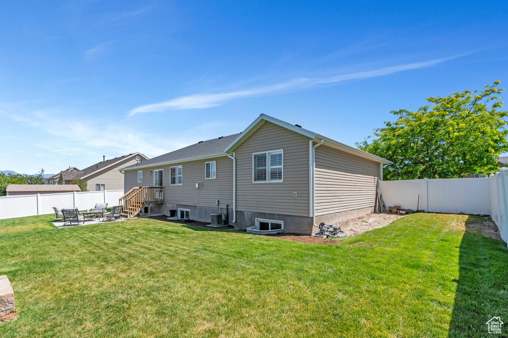 Rear view of property with a fenced backyard and a fire pit