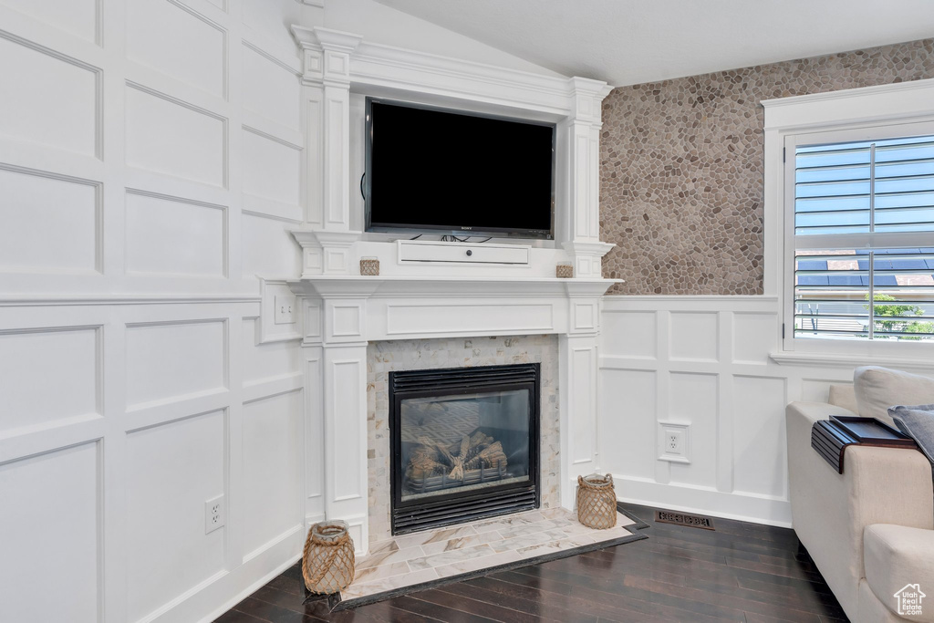 Detailed view of a decorative wall, wood finished floors, a fireplace with flush hearth, a wainscoted wall, and wallpapered walls