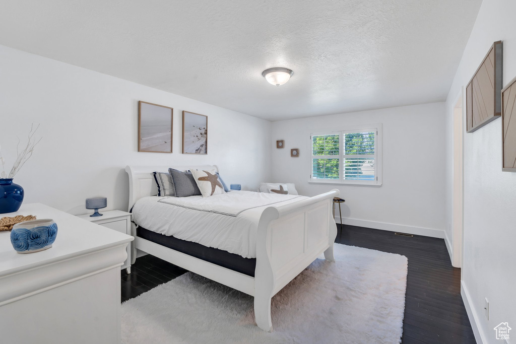 Bedroom with dark wood finished floors and a textured ceiling
