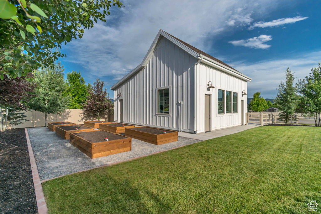 Back of property with board and batten siding, a vegetable garden, and a fenced backyard