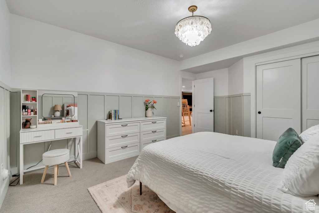 Bedroom featuring a chandelier, a wainscoted wall, light carpet, and a closet
