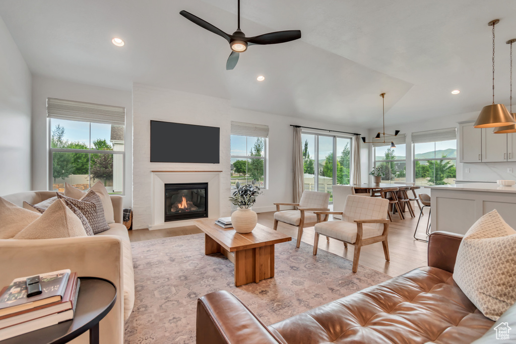Living area featuring healthy amount of natural light, a ceiling fan, light wood-style floors, recessed lighting, and a glass covered fireplace