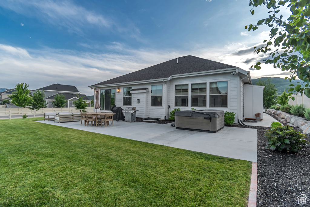 Back of house with a hot tub, a patio, an outdoor hangout area, and roof with shingles