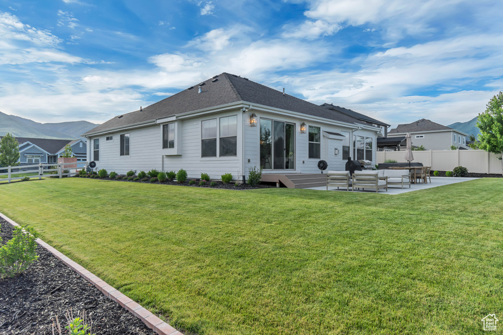 Rear view of property featuring a patio area, a shingled roof, a mountain view, and an outdoor living space