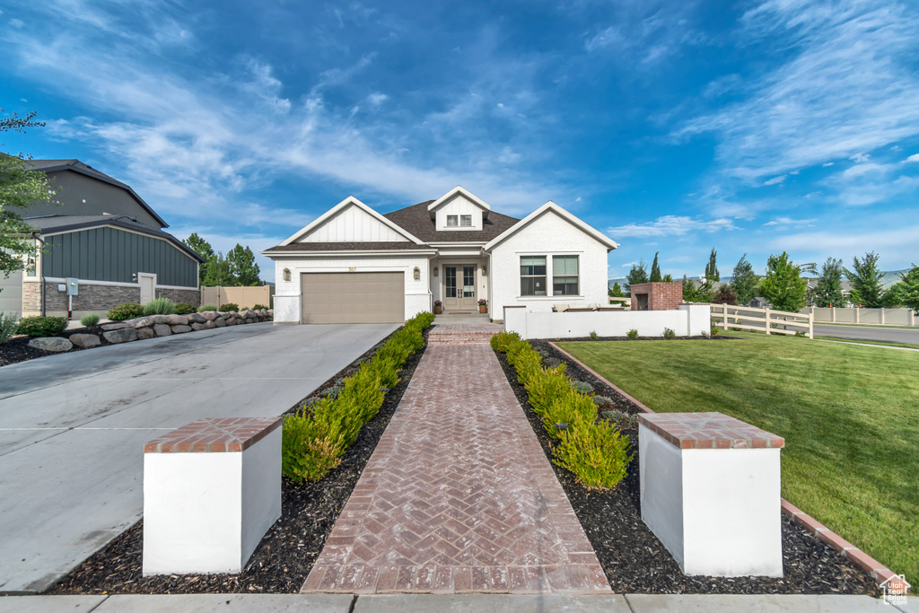 View of front of house featuring concrete driveway, french doors, and a garage