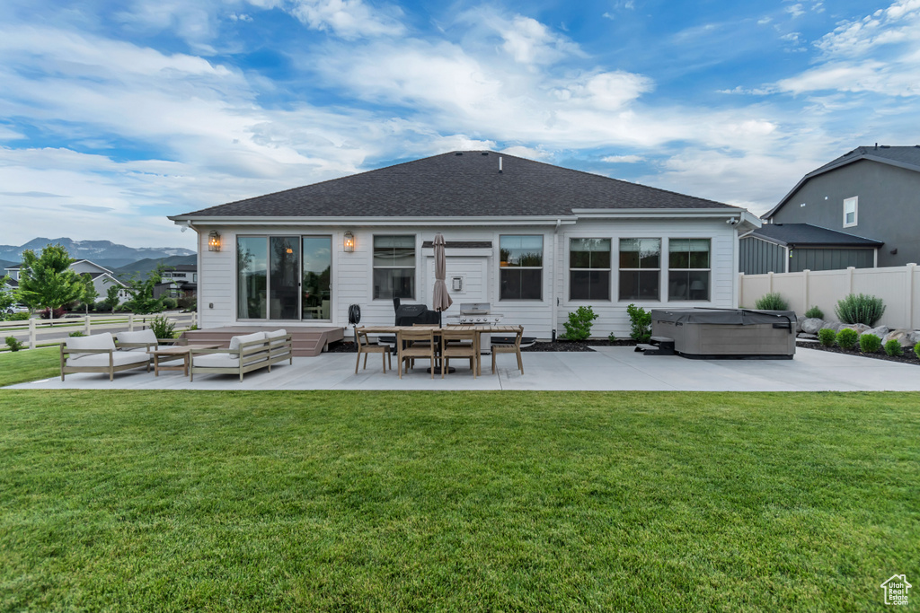 Rear view of house with a hot tub, a patio, outdoor lounge area, a mountain view, and a shingled roof