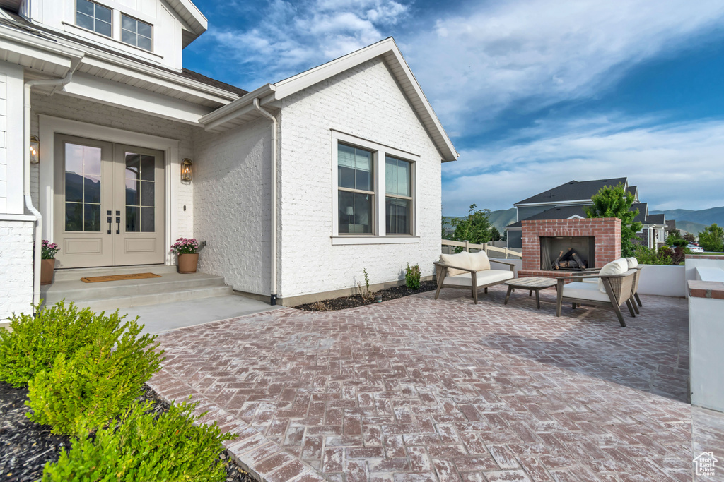 View of patio with french doors and an outdoor brick fireplace
