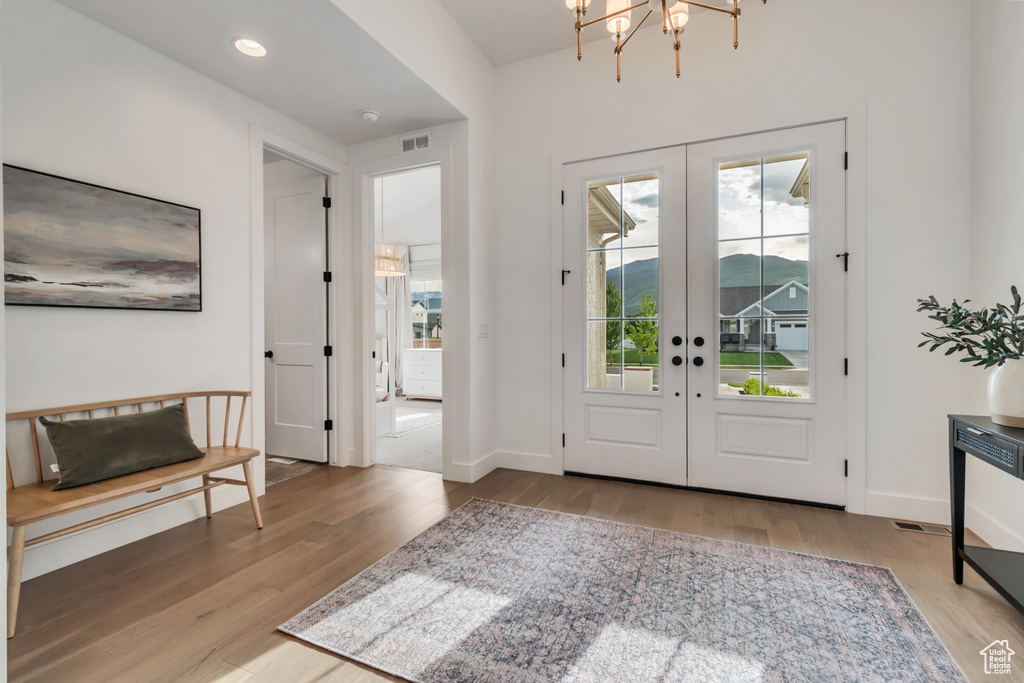 Foyer entrance with french doors, wood finished floors, a chandelier, and recessed lighting