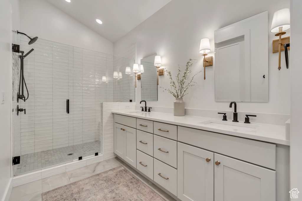 Full bathroom featuring double vanity, a stall shower, recessed lighting, lofted ceiling, and marble finish flooring