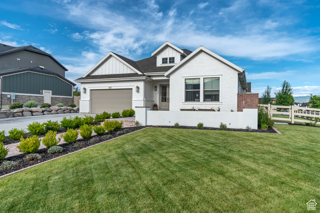 View of front of house featuring an attached garage, board and batten siding, driveway, and brick siding