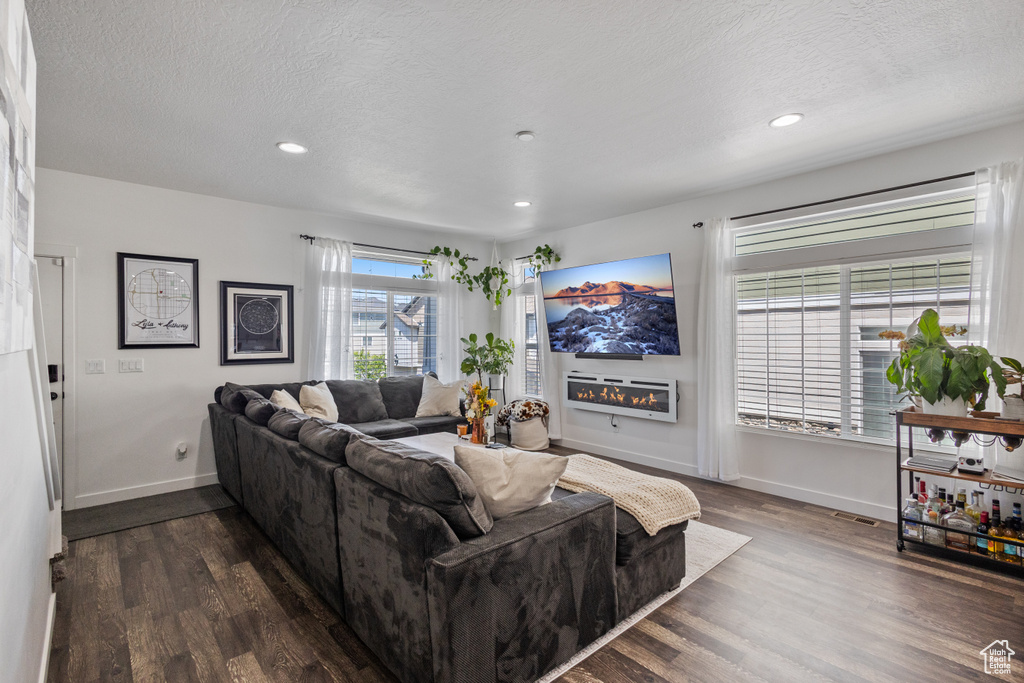 Living area with dark wood finished floors, recessed lighting, and a textured ceiling