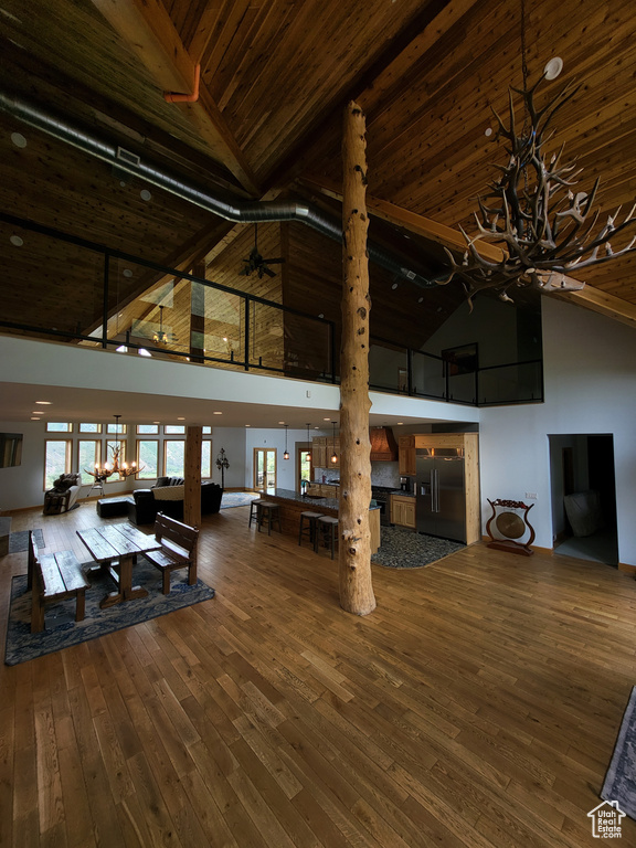 Living area with high vaulted ceiling, a wooden ceiling with exposed beams, hardwood / wood-style flooring, and a chandelier
